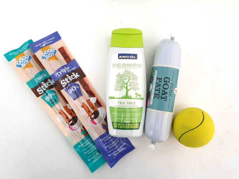 Gift Wrapped Christmas Bundles for pets with treats, dog shampoo, goat pâté, and tennis ball.