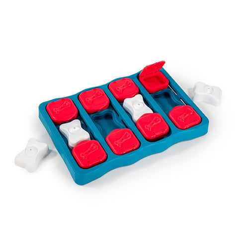 Nina Ottosson Dog Brick Interactive Treat Puzzle Dog Toy with red flip compartments and white bone pieces.