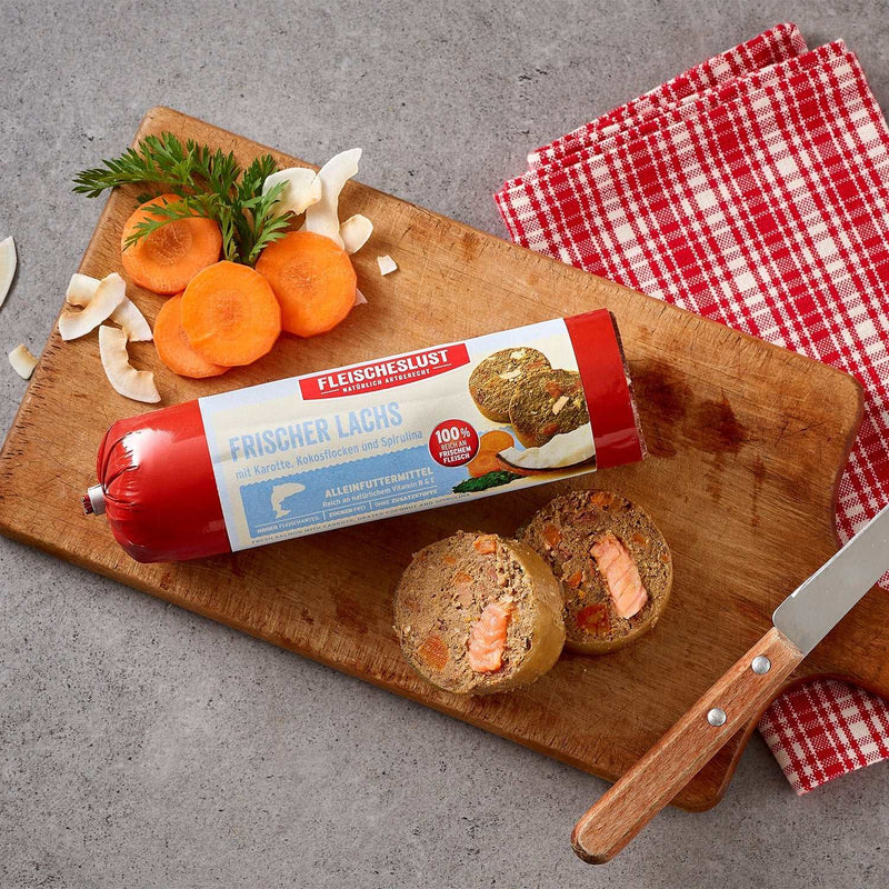Meatlove Salmon Complete food Chub Rolls for dogs with fresh salmon, rice, and carrots on a cutting board.