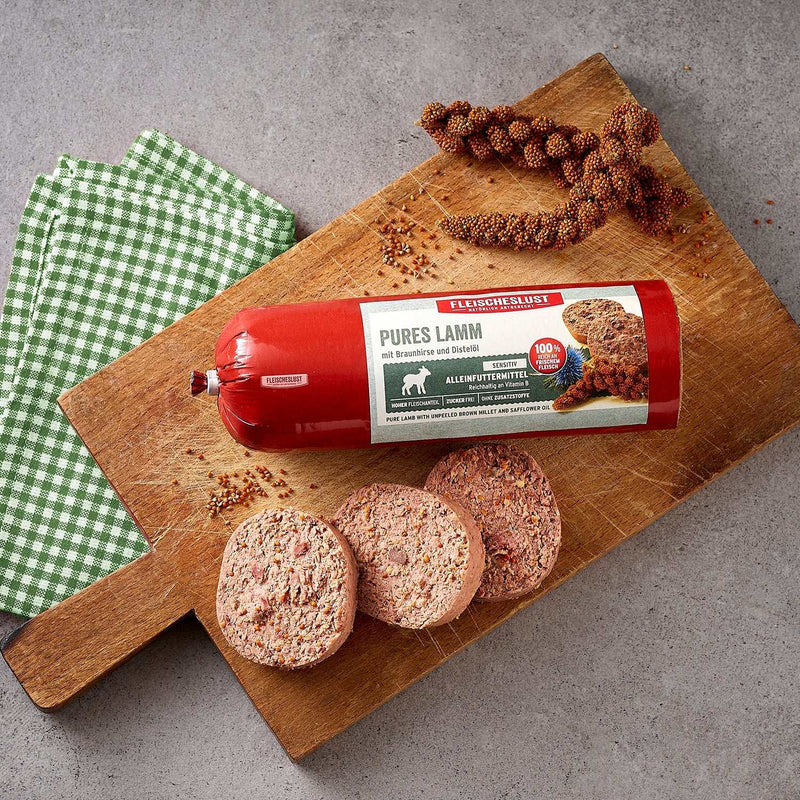 Meatlove Pure Lamb Single Protein Food Rolls for Dogs with unpeeled millet on cutting board.