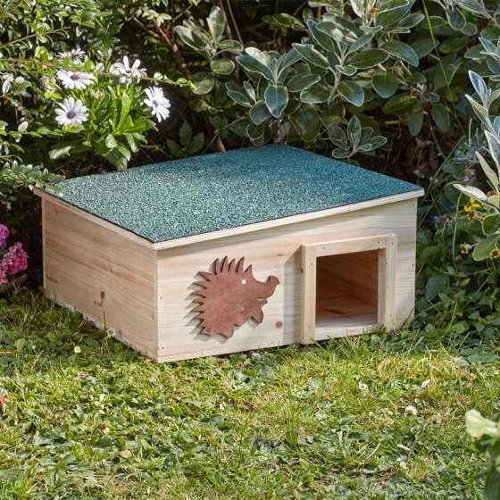 Hedgehog home with waterproof felt roof in a garden setting, featuring a safety entrance, ideal for wildlife conservation.