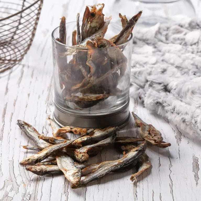 Hollings Natural Sprats Dog Treats in a glass container on a rustic table.